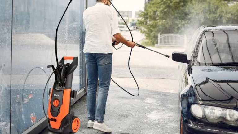 homem lavando carro preto com lavadora de alta pressão